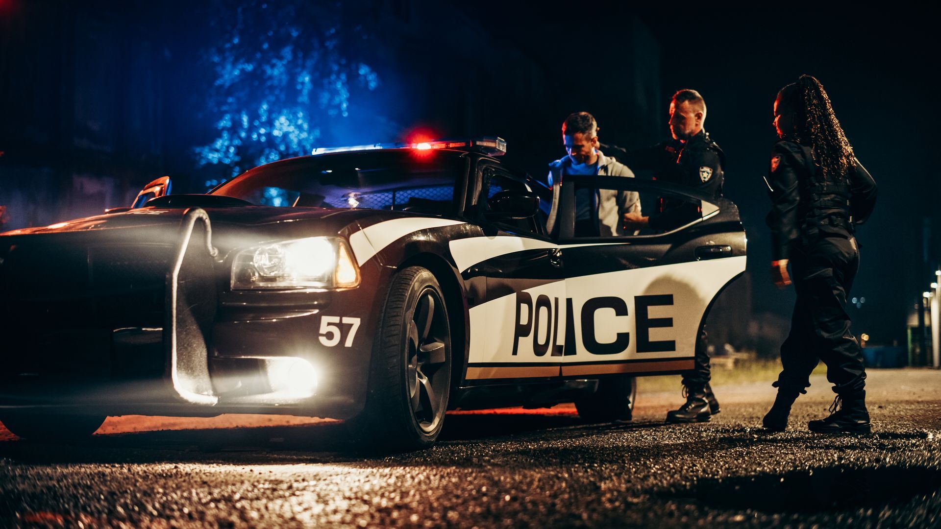 A police car is parked on the side of the road at night.