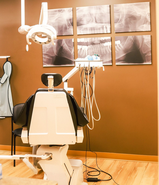 Dentist working on a patient in a modern dental clinic, with white cabinets and tools visible. Dentist working on a patient in a modern dental clinic, with white cabinets and tools visible.