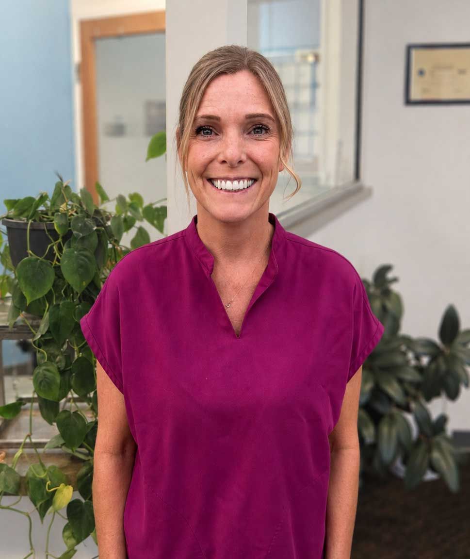 Smiling woman in a magenta top standing in an office lobby with plants. Smiling woman in a magenta top standing in an office lobby with plants.