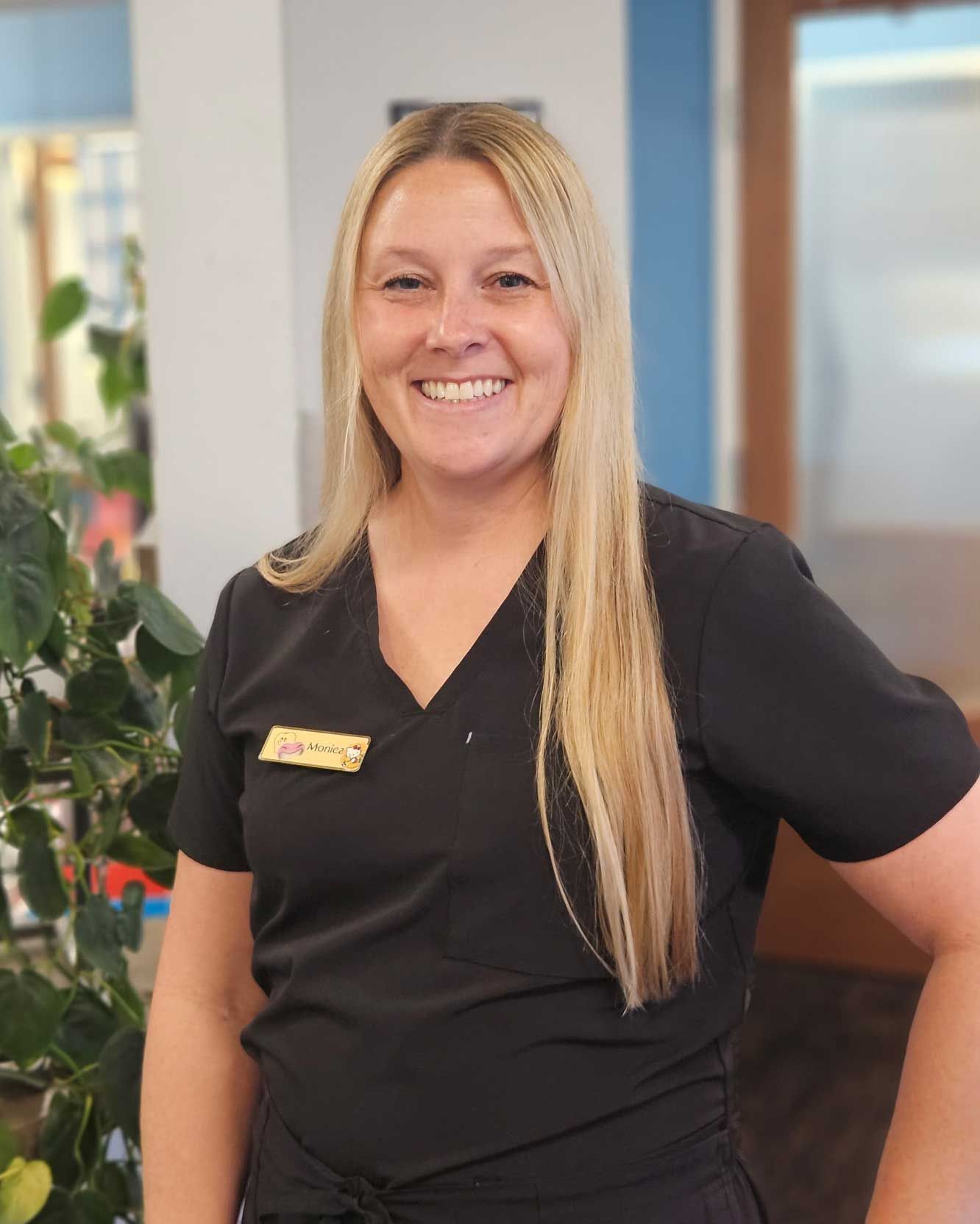 Smiling receptionist in black scrubs standing in an office lobby Smiling receptionist in black scrubs standing in an office lobby