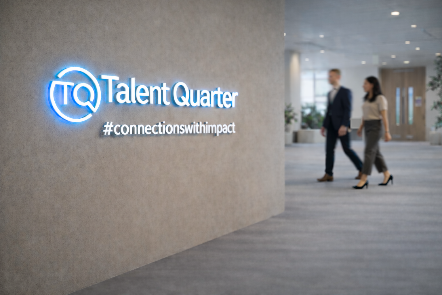 Two blurred people walking through an office past a glass-walled conference room with an indoor plant.