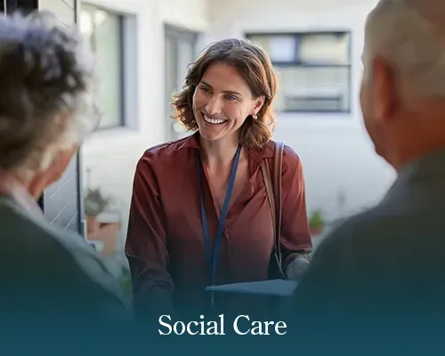 Social care worker smiling and talking with two people outdoors