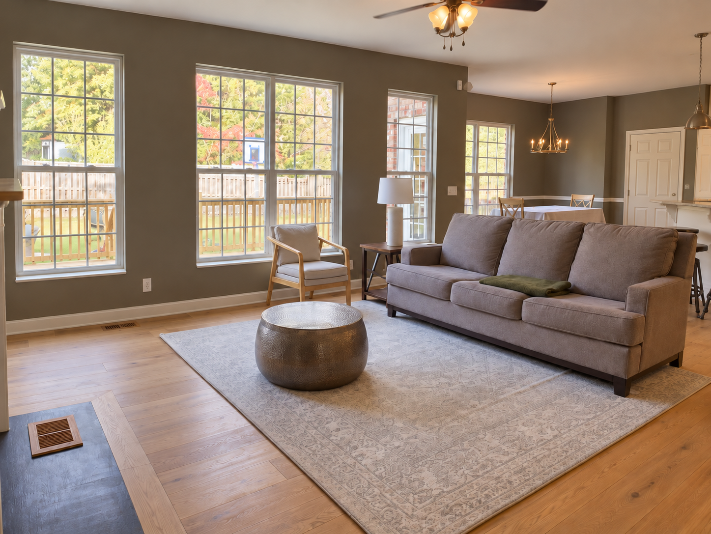 Modern living room with patterned accent wall, dining table, chandelier, and fireplace with seating area