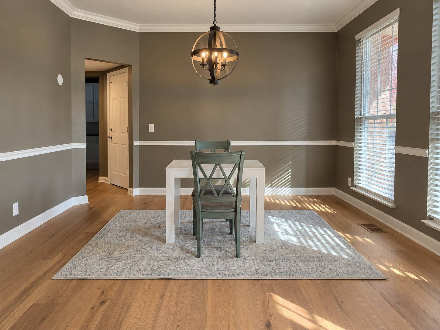 Open-plan living room and kitchen with light wood floors, white walls, and modern furniture.
