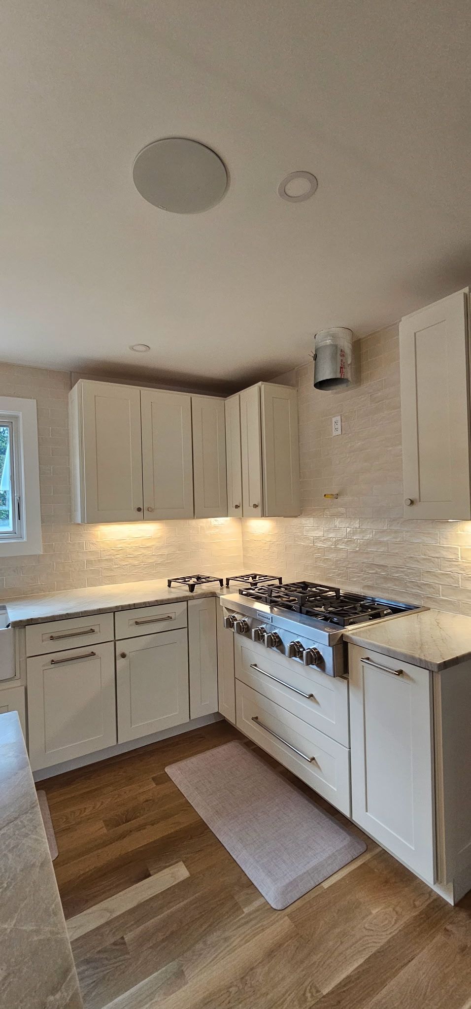 Bright kitchen with white cabinets, granite counters, tiled backsplash, and stainless steel appliances.