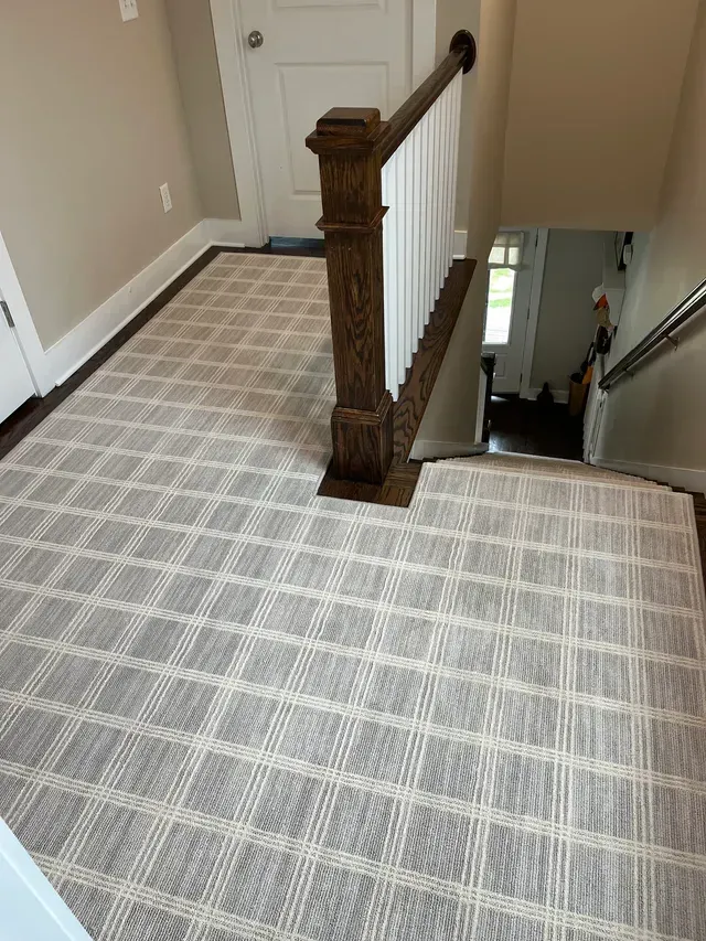 Carpeted upstairs landing with wooden banister and staircase opening to lower floor.