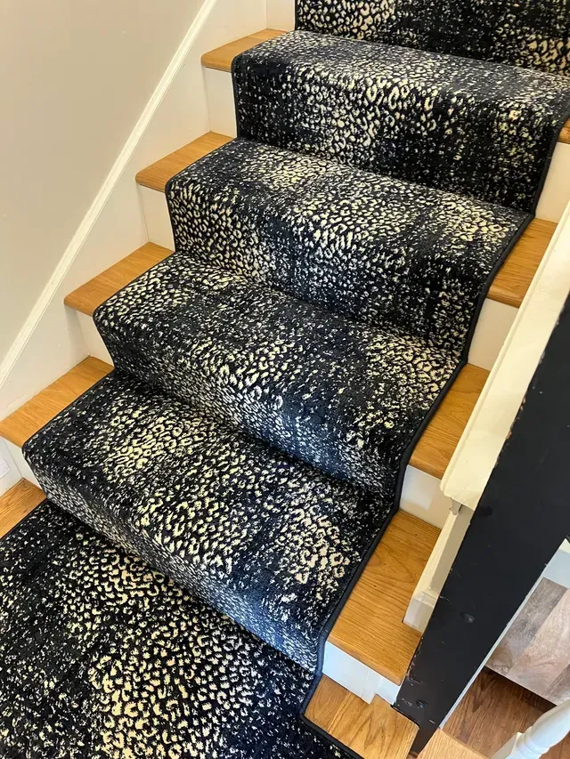 Carpeted stairs with a black-and-white speckled runner in a home interior