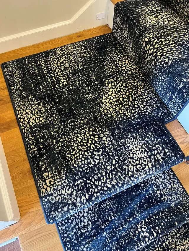 Patterned dark blue and white rug on hardwood floor beside a couch.