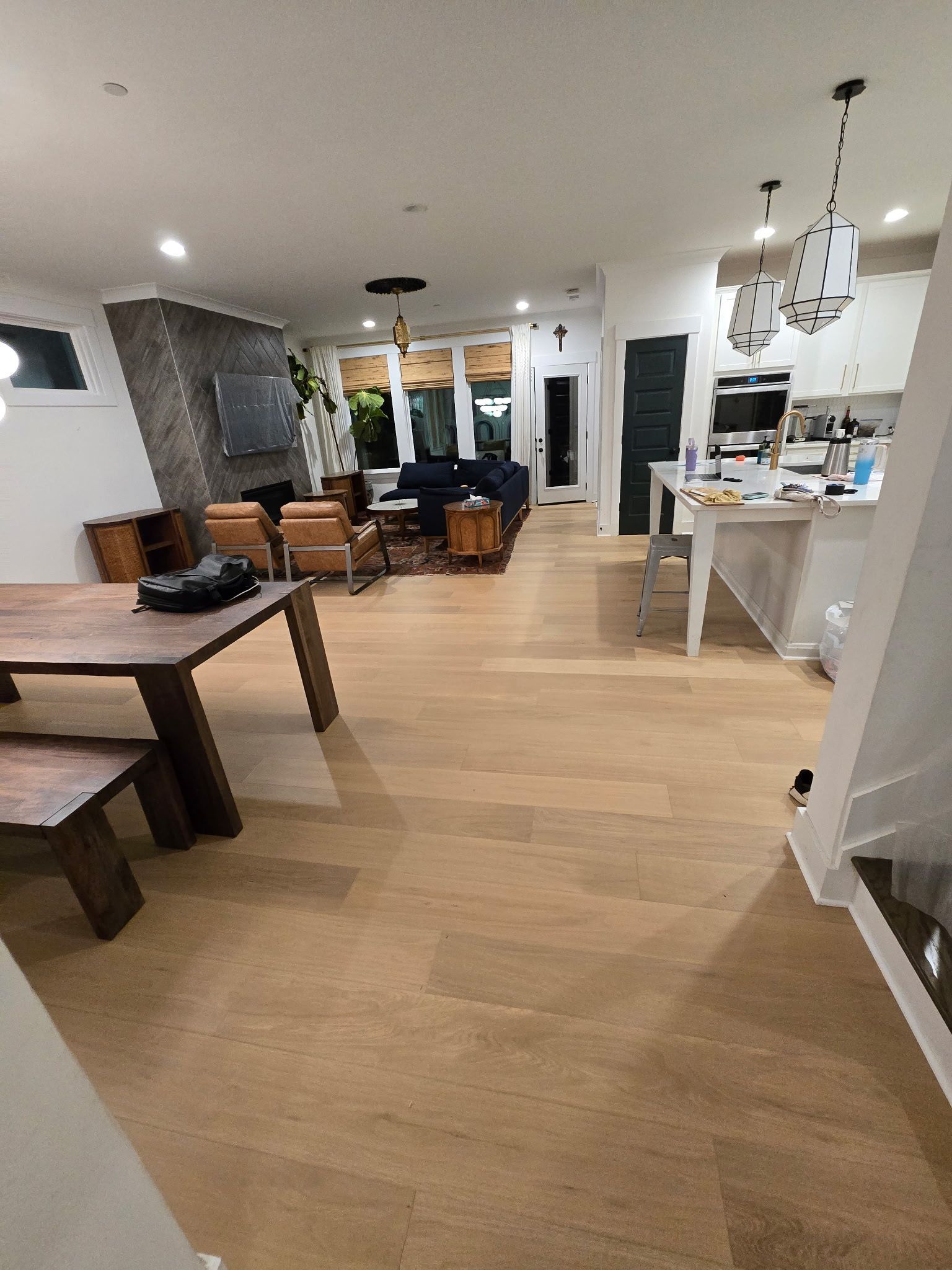 Open-plan living room and kitchen with light wood floors, white walls, and modern furniture.