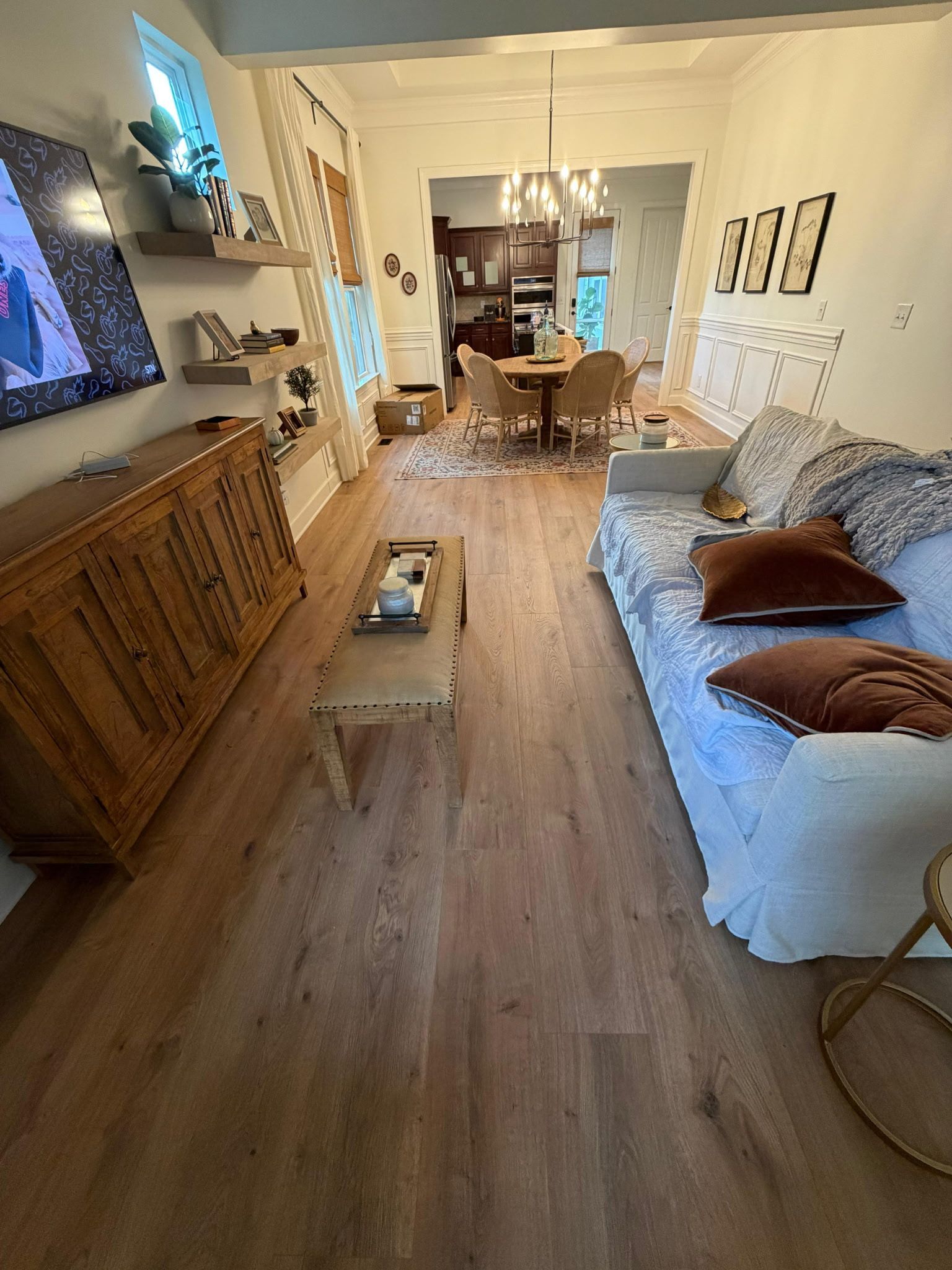 Cozy living room with wood floor, sofa, TV, cabinet, coffee table, and open doorway to dining area.