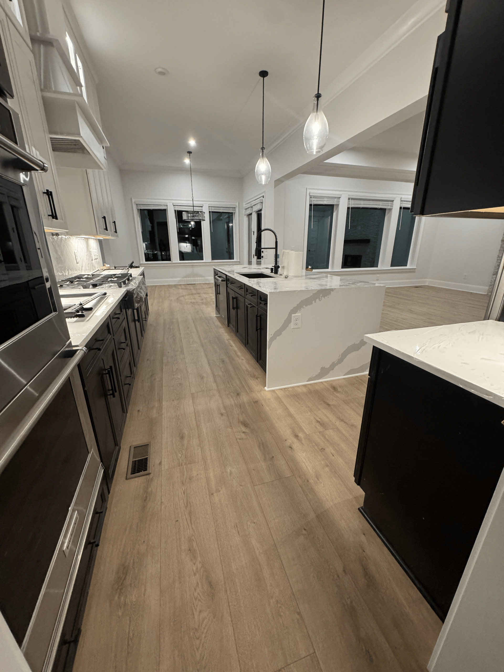 Modern white kitchen with dark cabinetry, island, pendant lights, and wood flooring