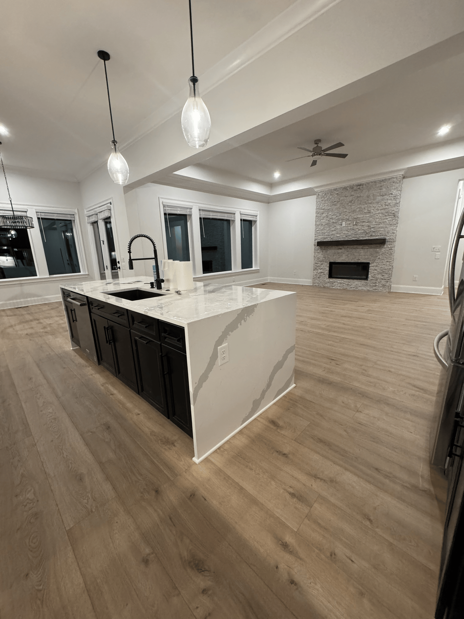 Modern open-concept kitchen and living area with large island, pendant lights, and fireplace.