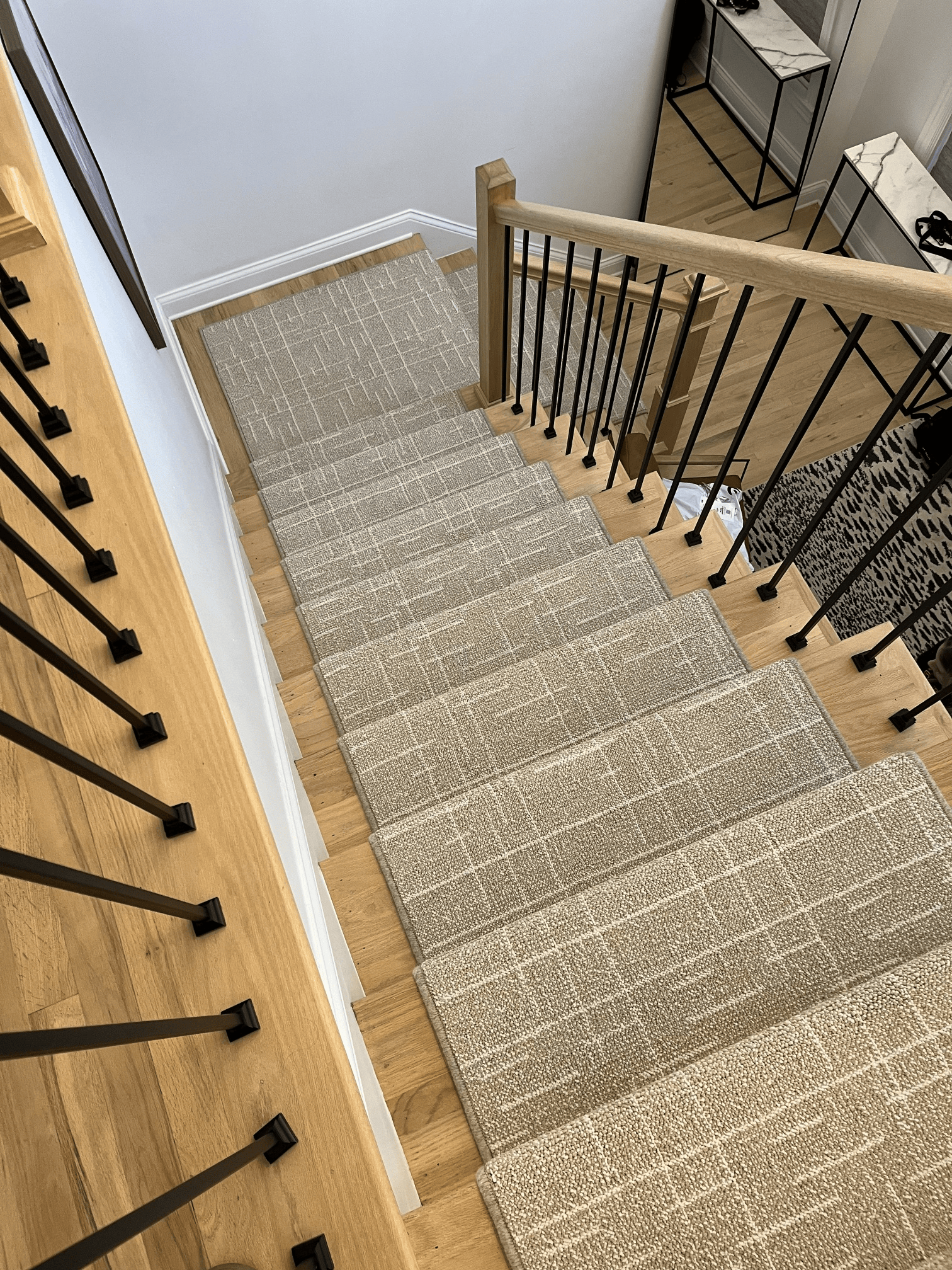 Carpeted staircase with black metal railing and light wood trim in a home interior.