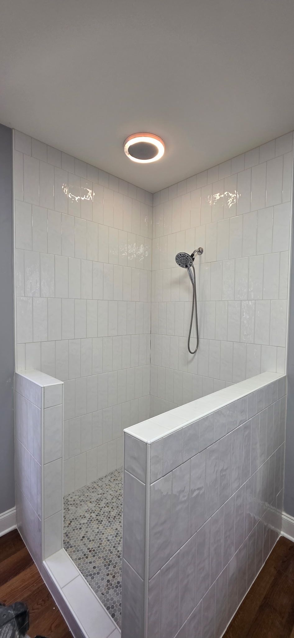 Bathroom shower with beige tile walls, pebble floor, and built-in niche