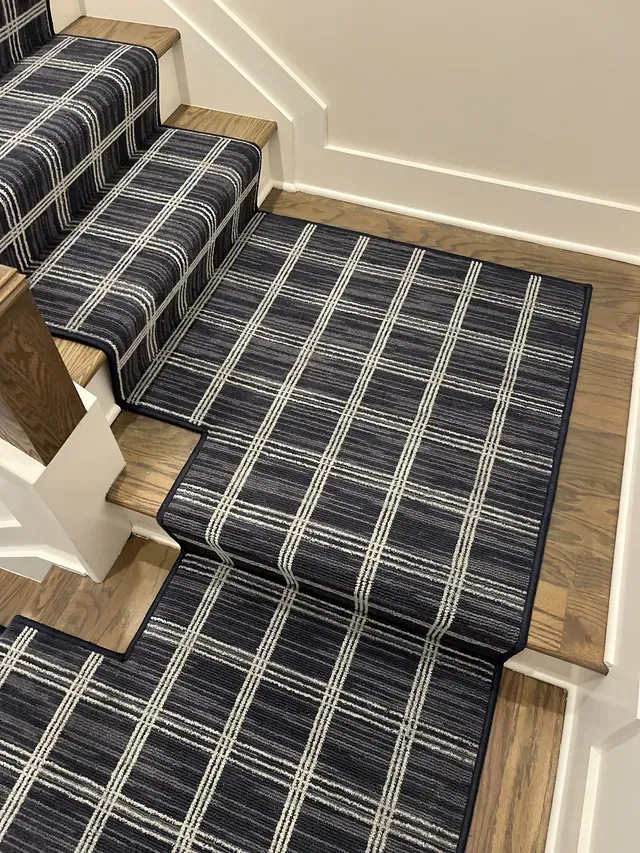 Staircase with a navy and white patterned carpet runner on wooden steps