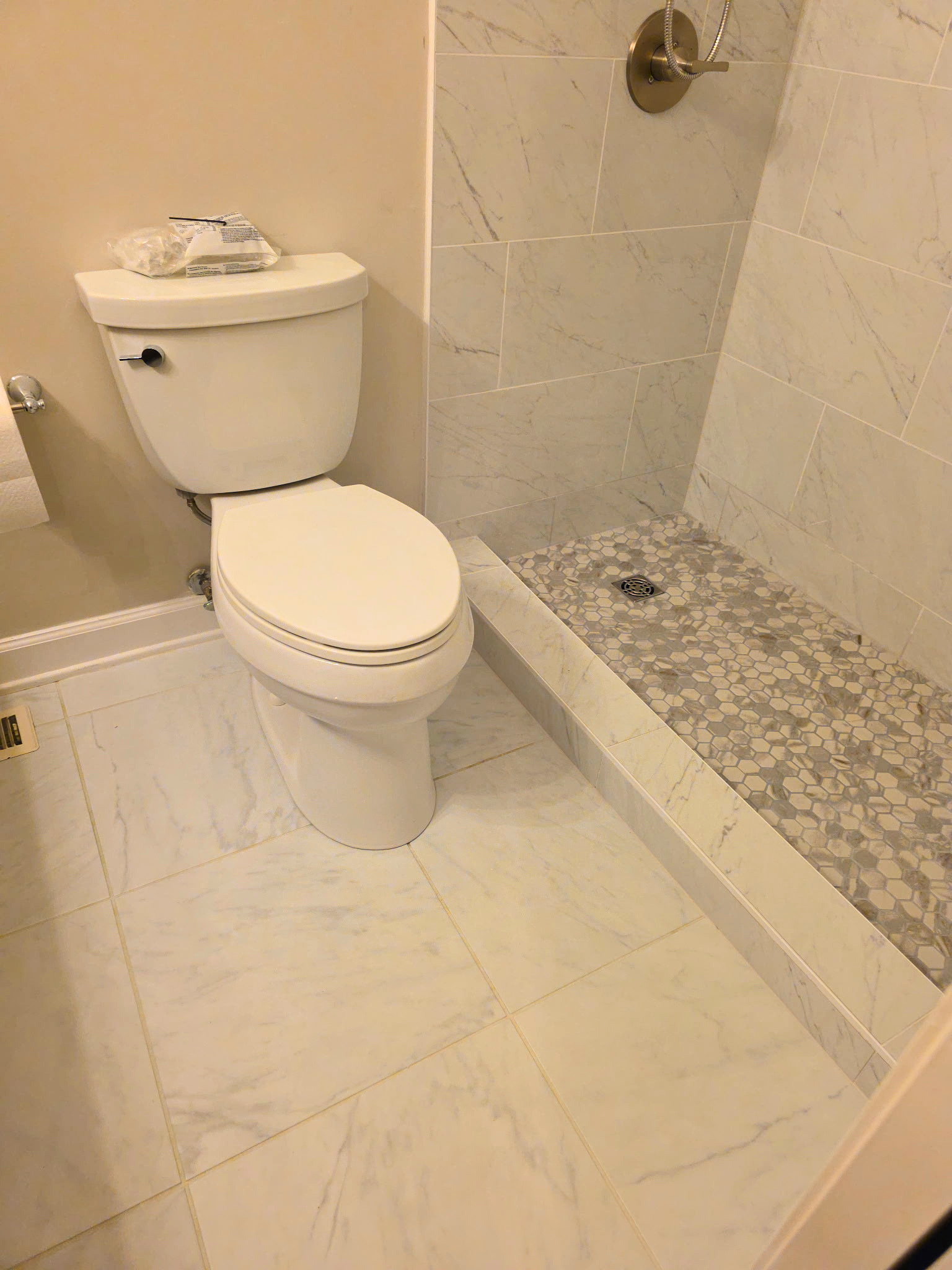 Small bathroom with a white toilet beside a tiled shower stall.