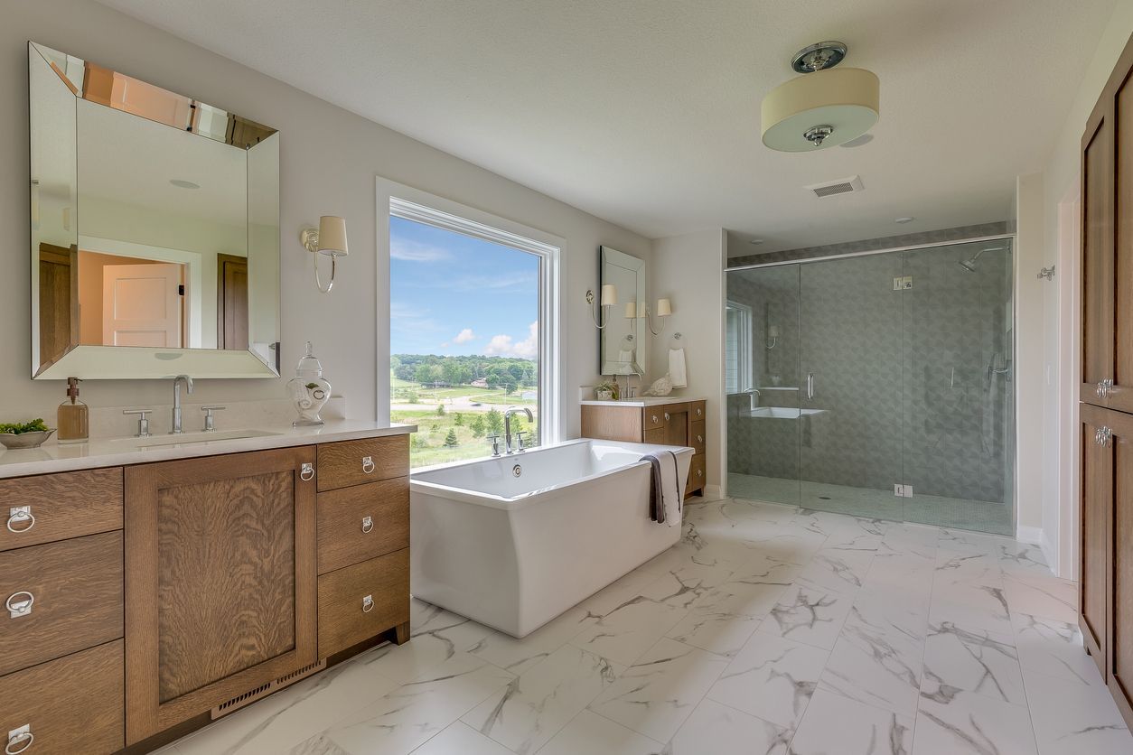 Luxurious bathroom with double vanity, freestanding tub, large window, and glass-enclosed shower