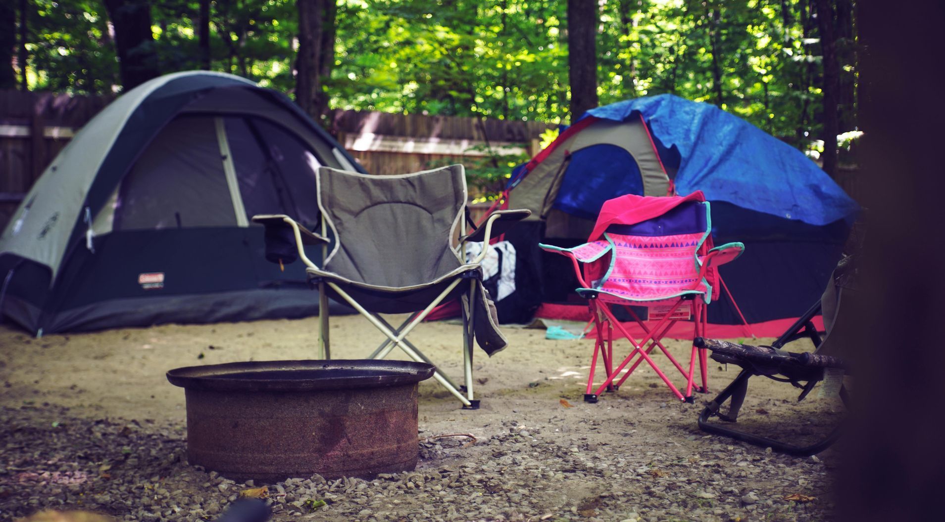 A group of tents and chairs are sitting around a fire pit.