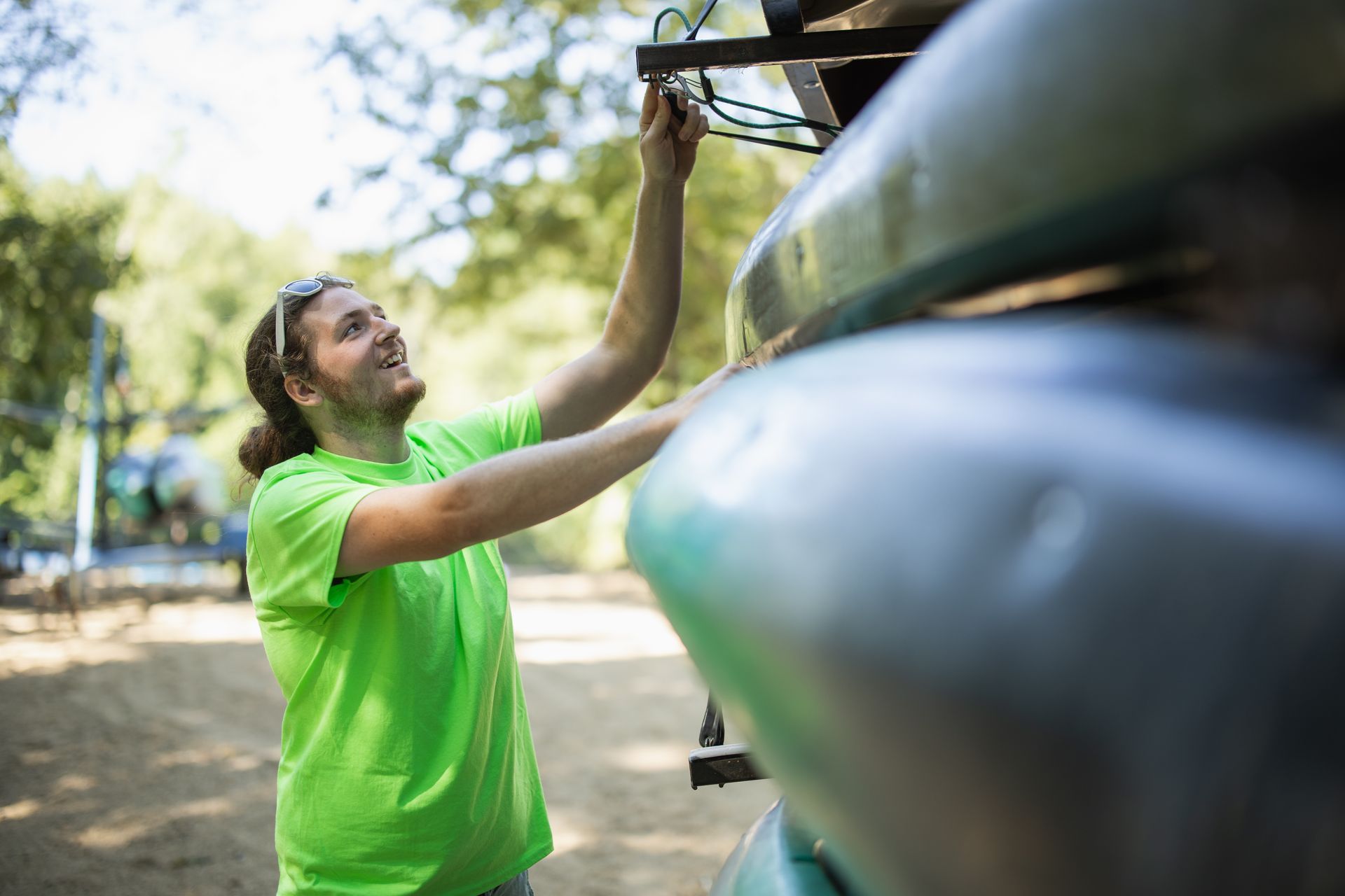 Person in a bright green shirt inspecting a large green canoe outdoors