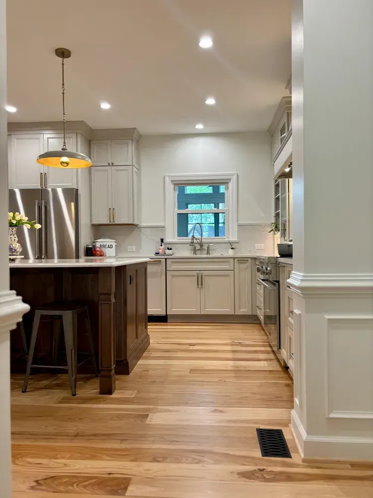 Bright kitchen with white cabinets, wood floors, island seating, and a window over the sink.