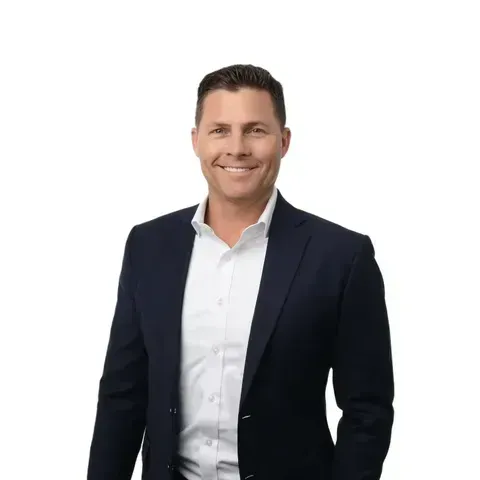 A man in a suit and white shirt is smiling for the camera.