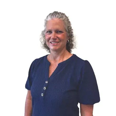 A woman in a blue shirt is smiling for the camera.