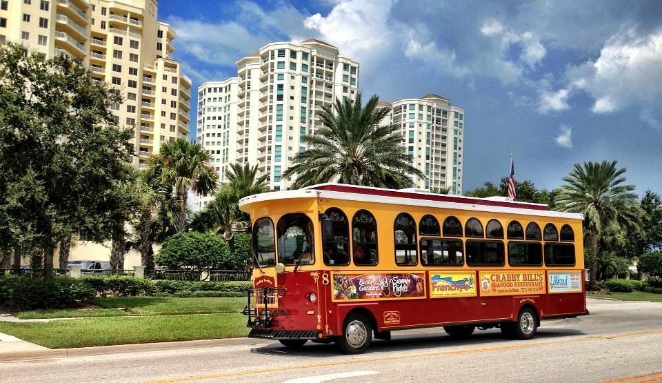 A red and yellow trolley is driving down a street in front of tall buildings