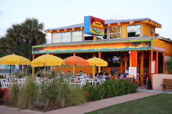 A restaurant with tables and umbrellas in front of it