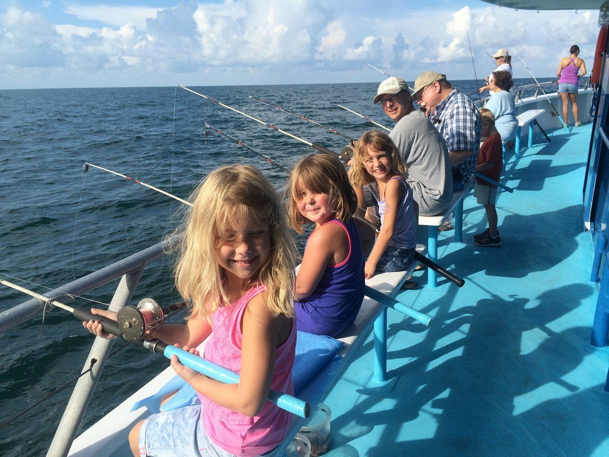 A group of children are fishing on a boat in the ocean.