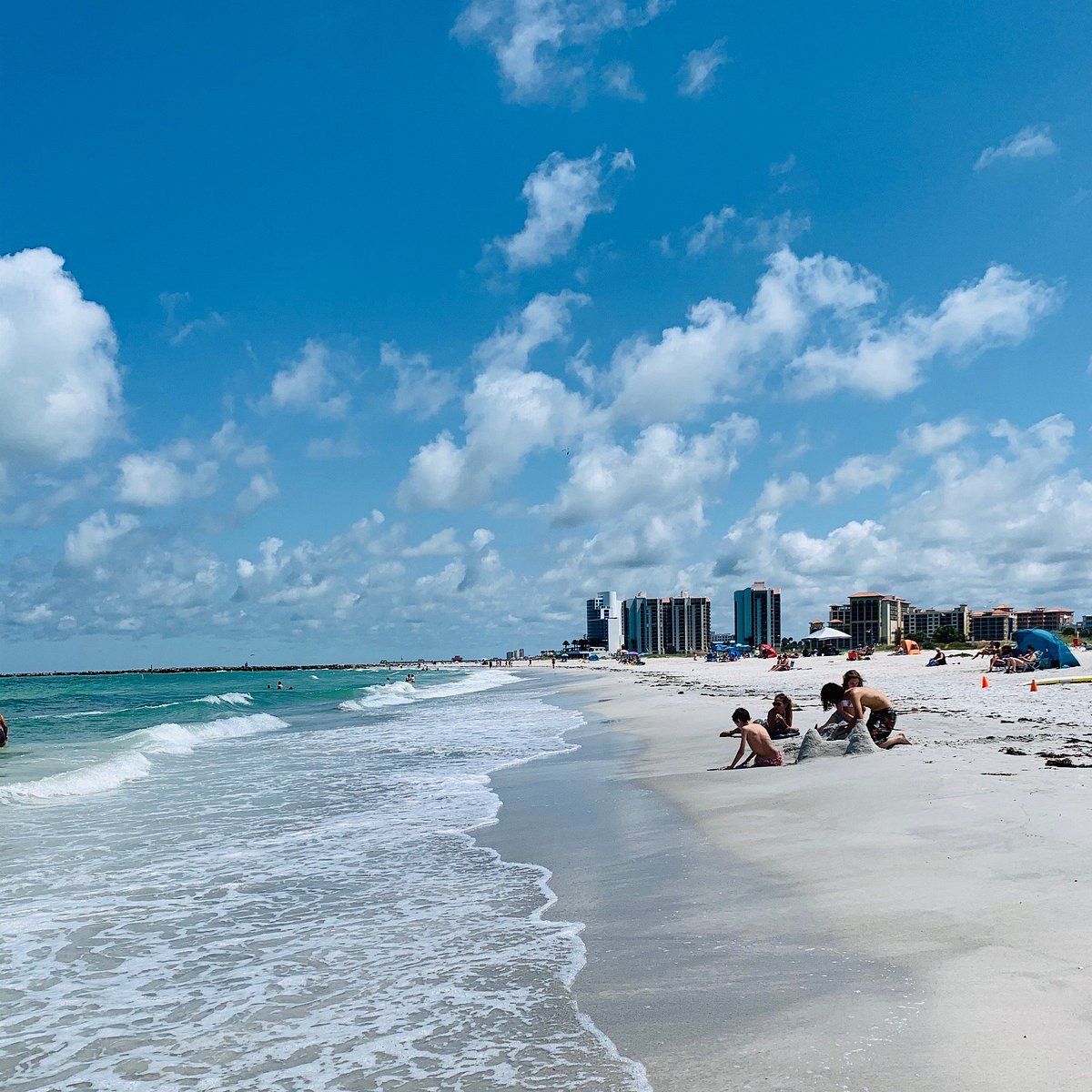 A group of people are sitting on the beach near the ocean
