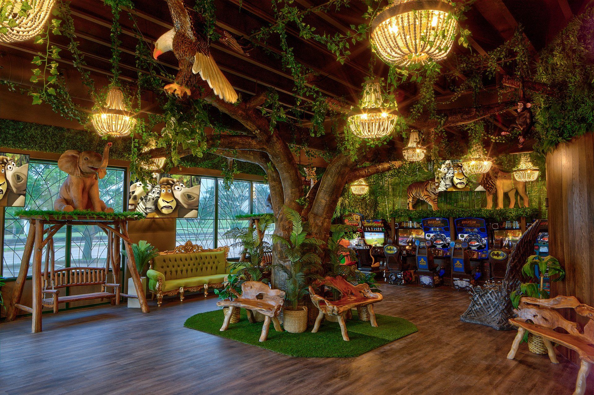 Tropical indoor lounge with hanging lights, lush greenery, and wooden seating under a vine-covered ceiling