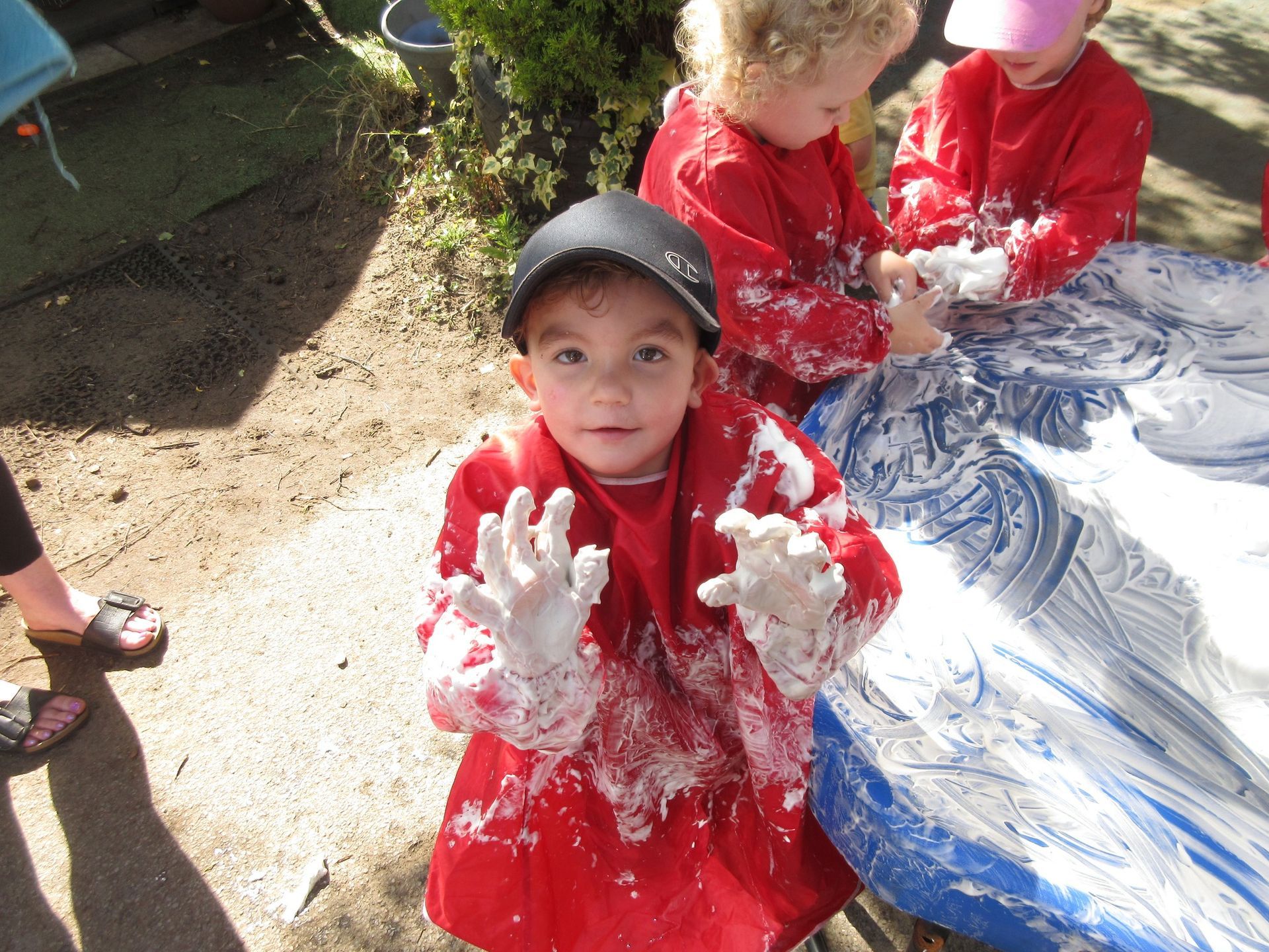 A little boy in a red shirt is covered in foam
