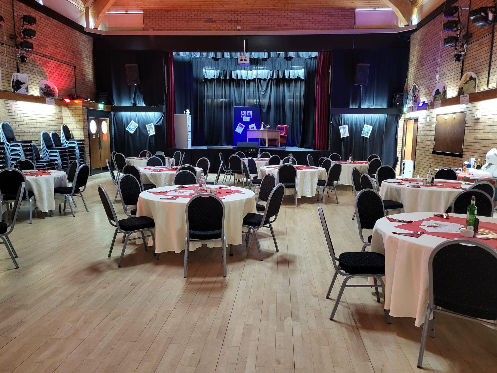 A large room filled with tables and chairs with a stage in the background.