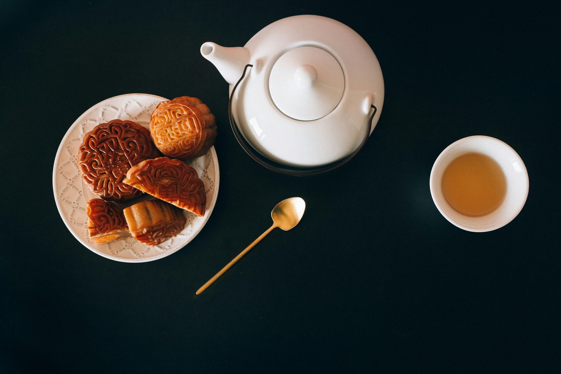 A plate of cookies , a teapot , and a cup of tea on a table.