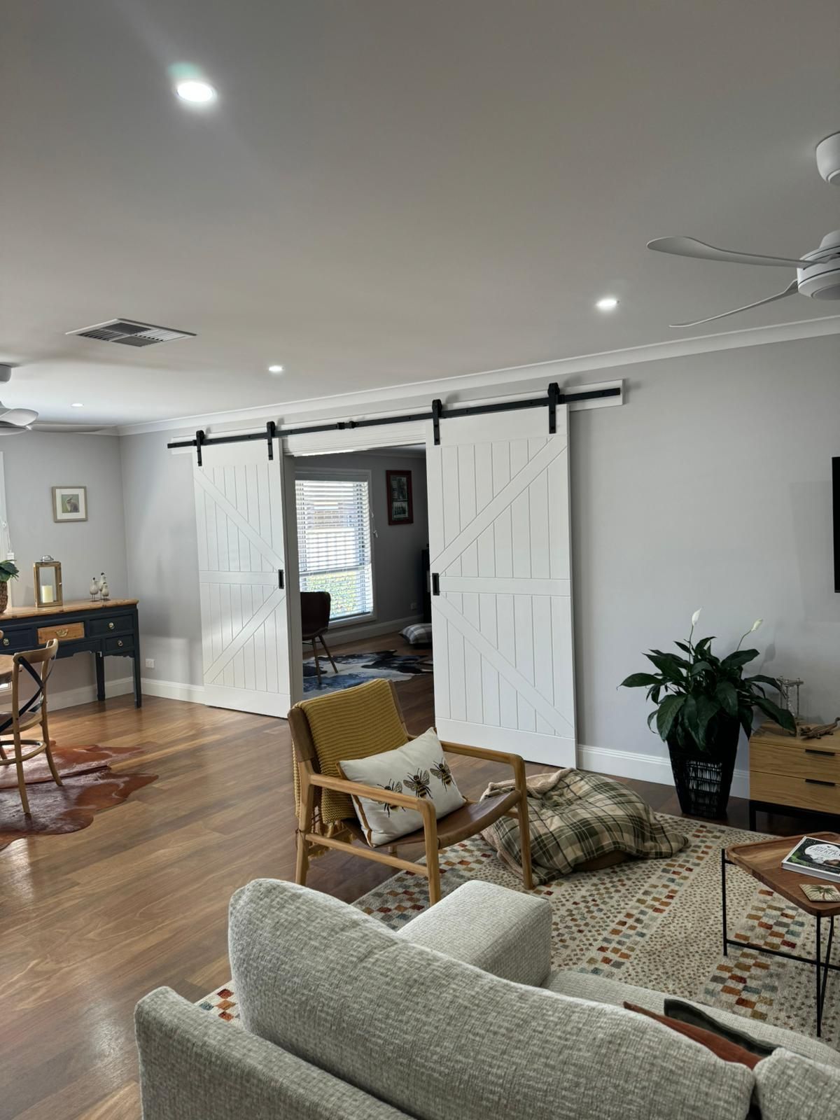 Living Room With White Barn Doors, Wooden Floors, and Modern Furniture — Andrew Harper Painting & Decorating in Albury, NSW