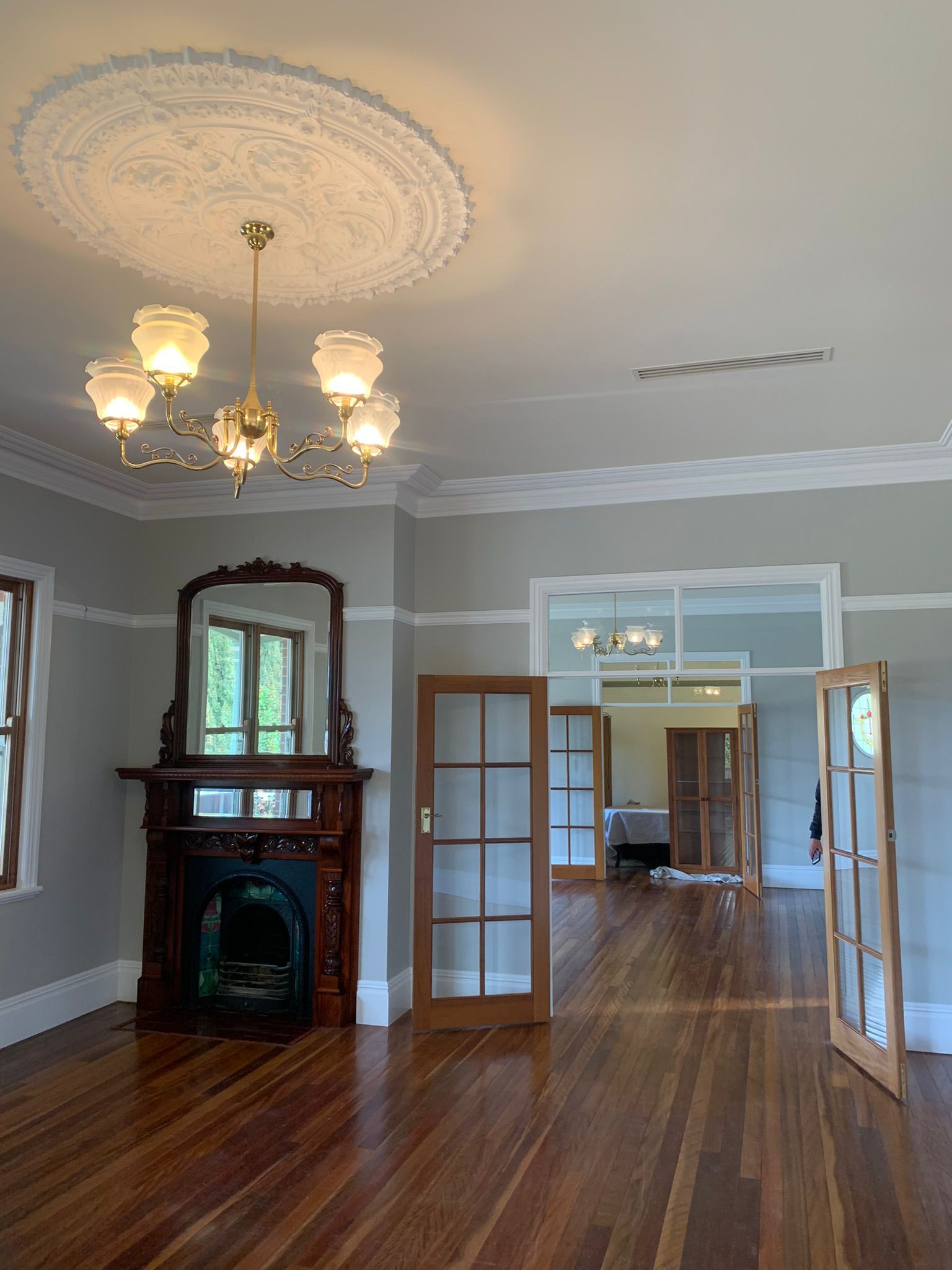 Empty room with fireplace, hardwood floor, chandelier, and multiple doorways — Andrew Harper Painting & Decorating in Albury, NSW
