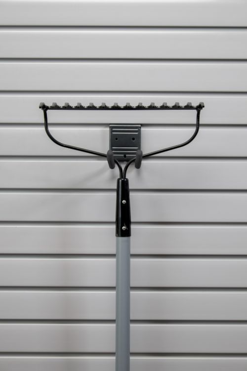 A rake is hanging on a hook on a wall.