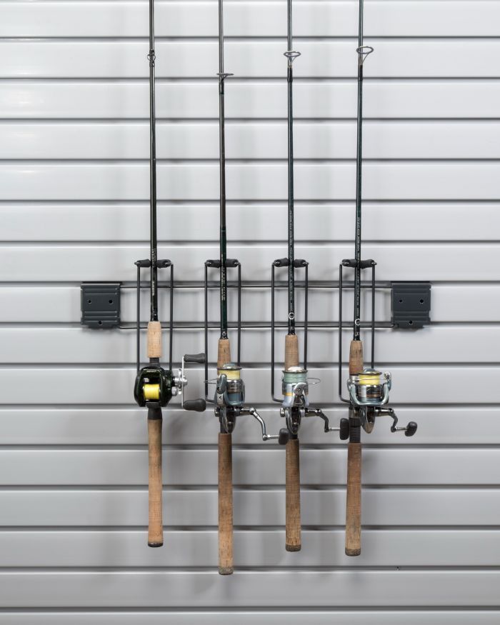 Four fishing rods and reels are hanging on a wall.
