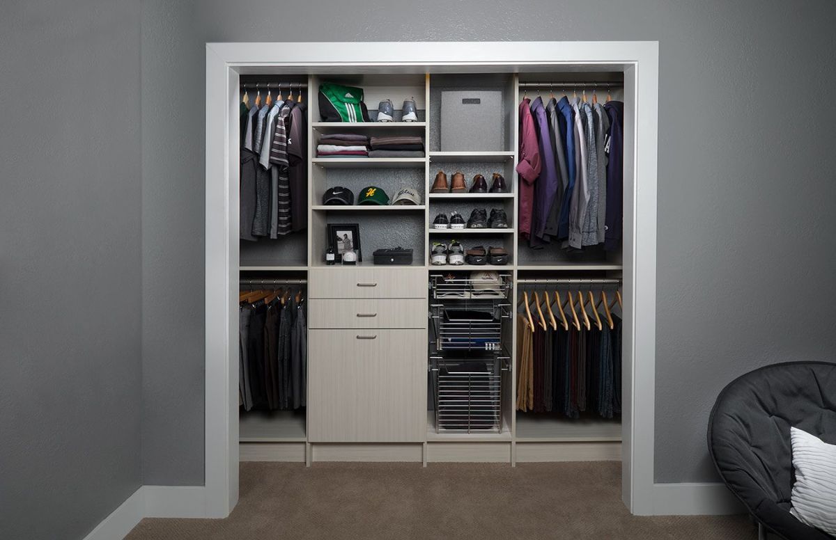 A closet filled with clothes and shoes in a room with a chair.