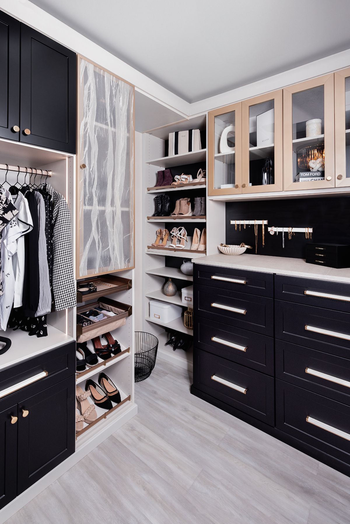 A walk in closet with black cabinets and glass doors