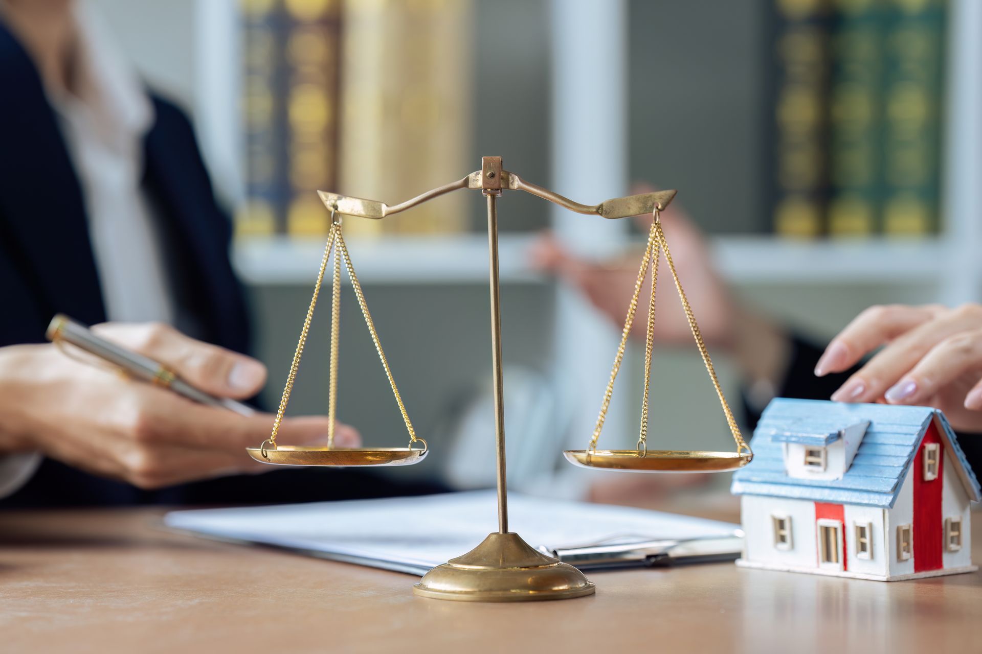 A lawyer and client talking with the scale of law and a residential house model. A lawyer and client talking with the scale of law and a residential house model.