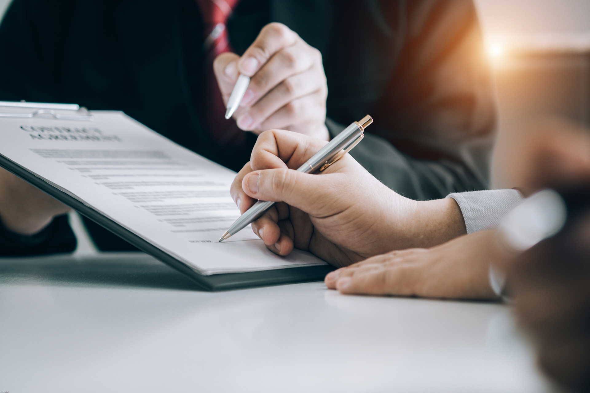 Local real estate attorney reviewing and signing sales contract with clients.