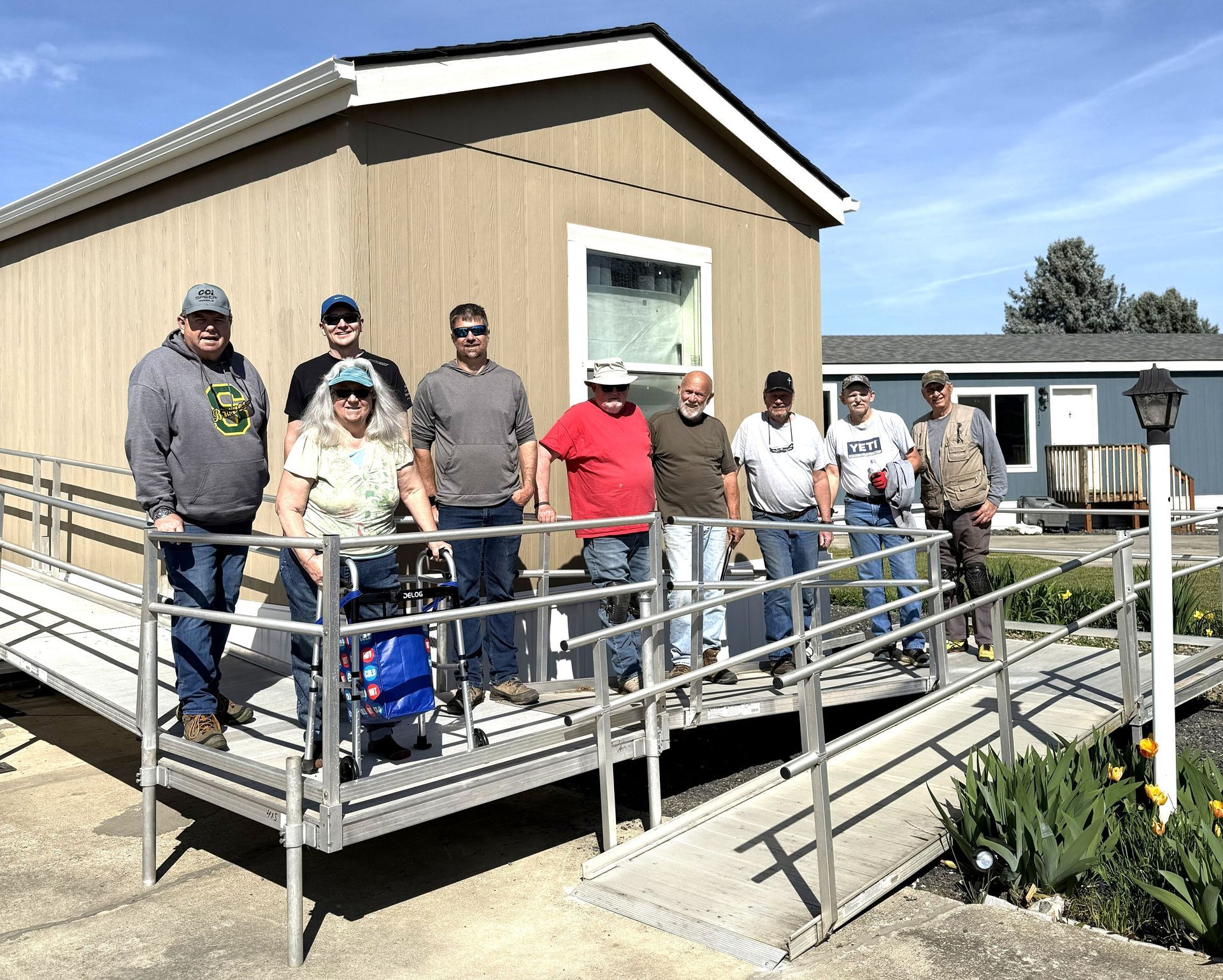 Group of people standing on a ramp outside a tan building on a sunny day