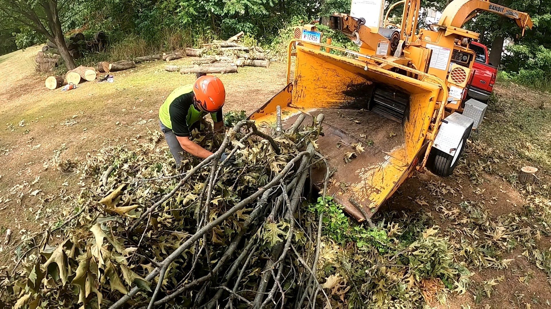 A man is working on a tree chipper in a yard.