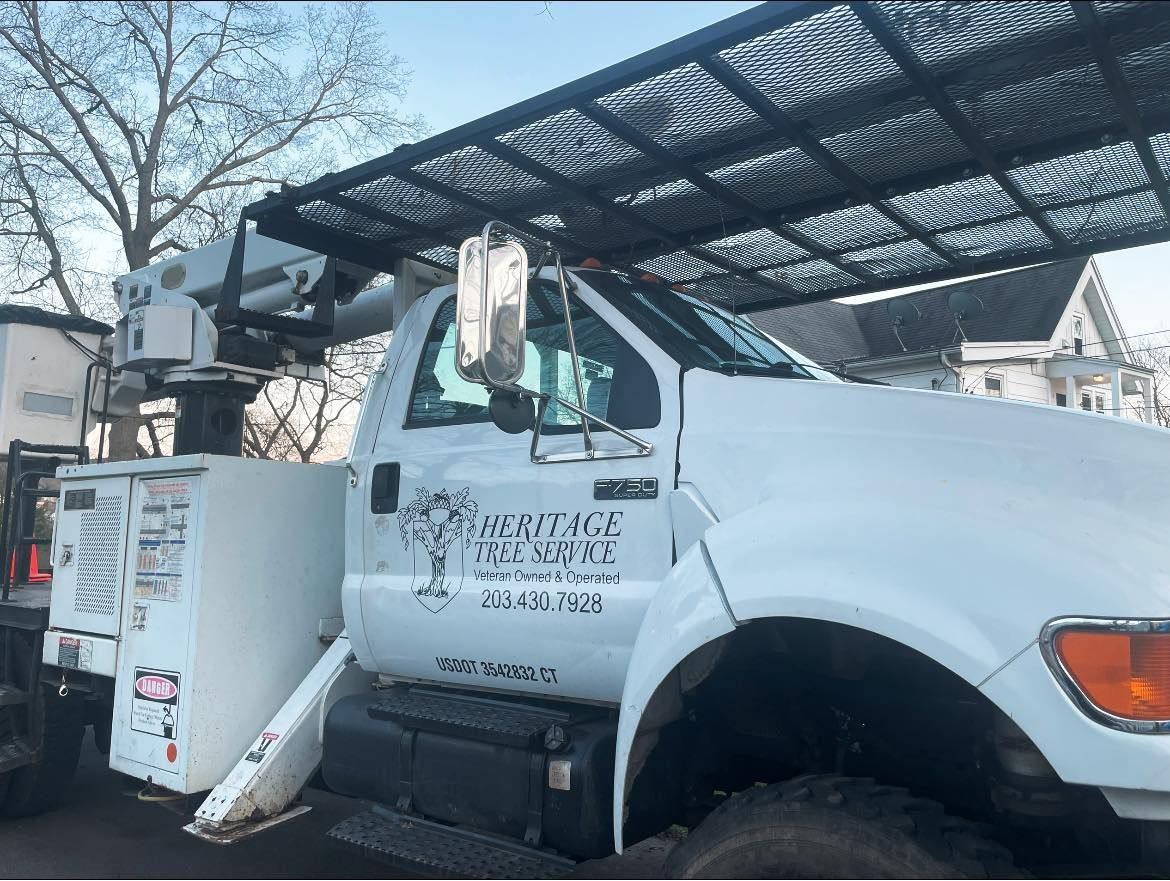 A white heritage tree service truck is parked in a parking lot