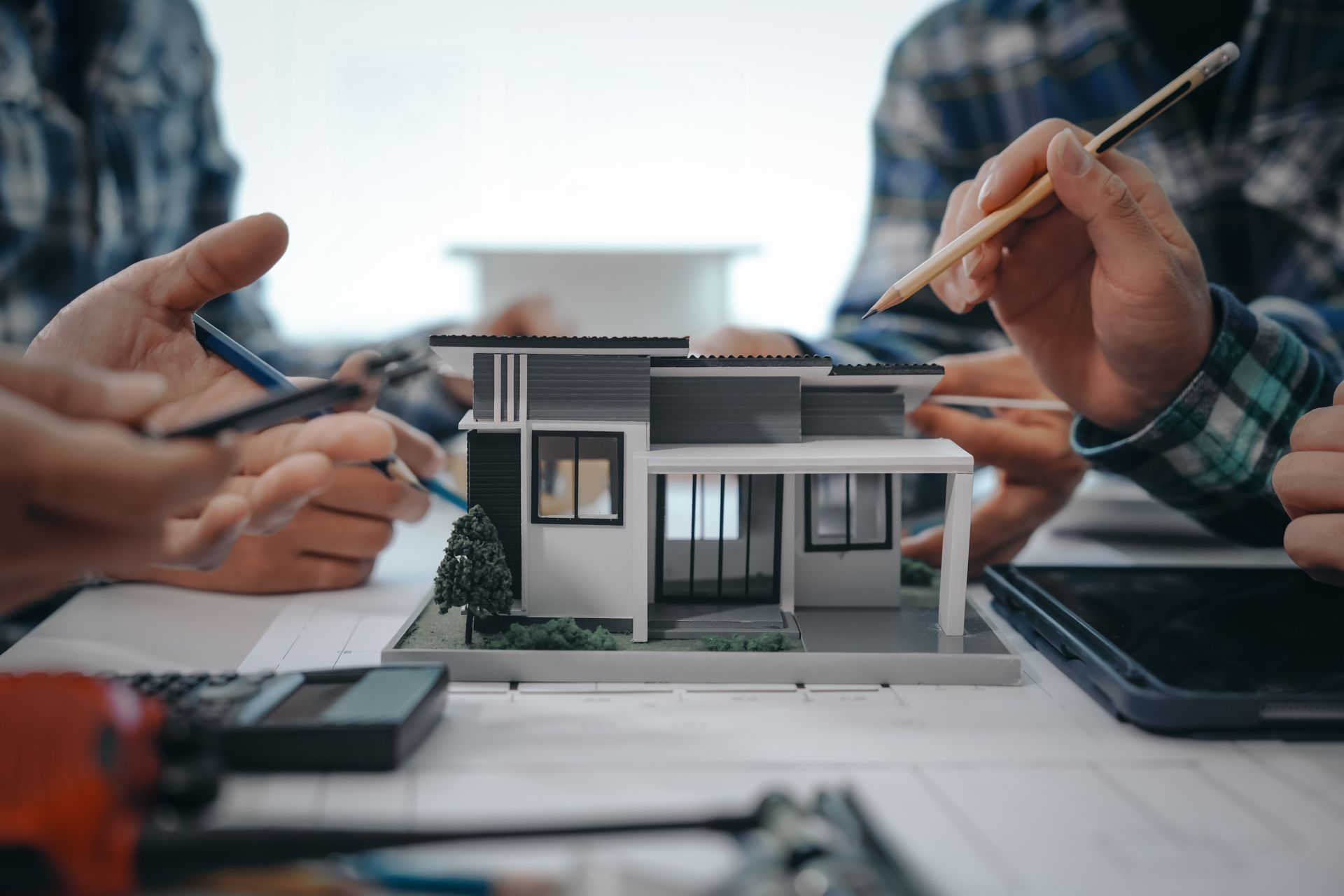 Board members reviewing a house model and plans during a Hawaii condominium management meeting.