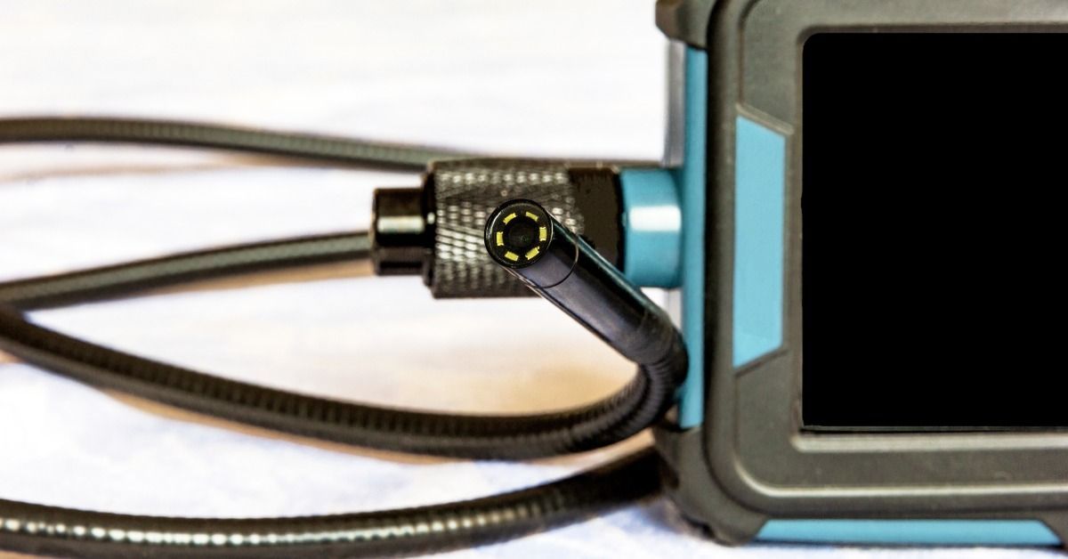 A flexible endoscope inspection camera resting on a table with a coiled cable and control unit.