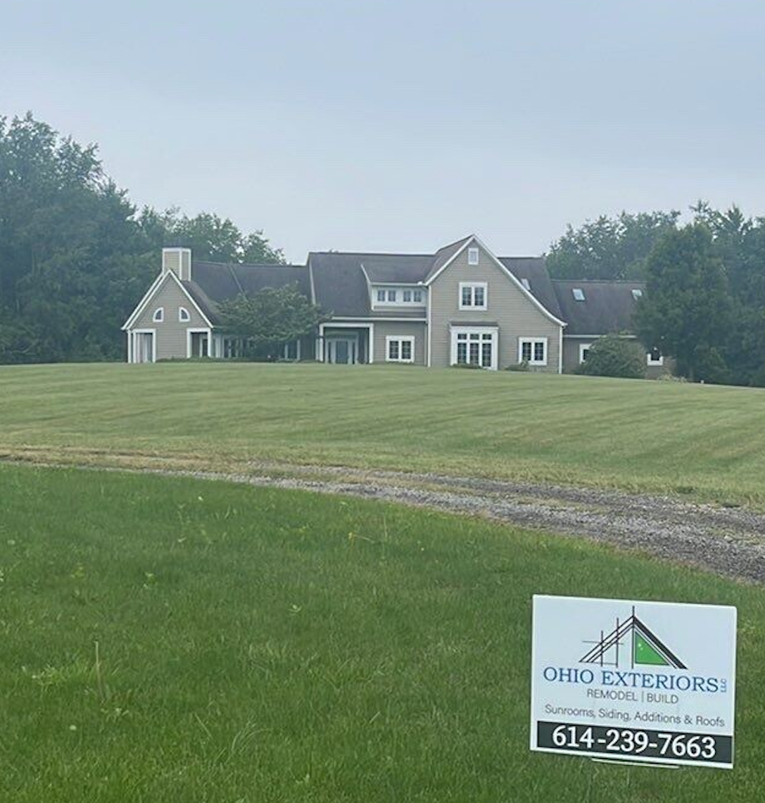 Large gray house and lawn with an Ohio Exteriors sign in the foreground