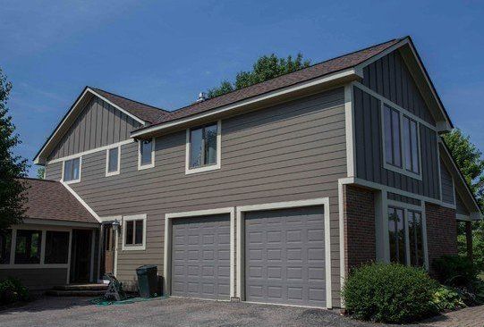 Two-story gray house with a double garage and front landscaping under a blue sky