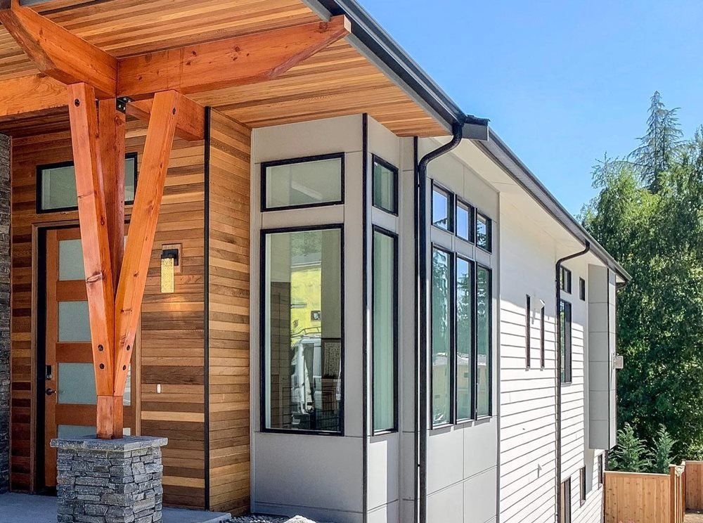 Modern house exterior with wood and white siding, large windows, and a covered entry porch